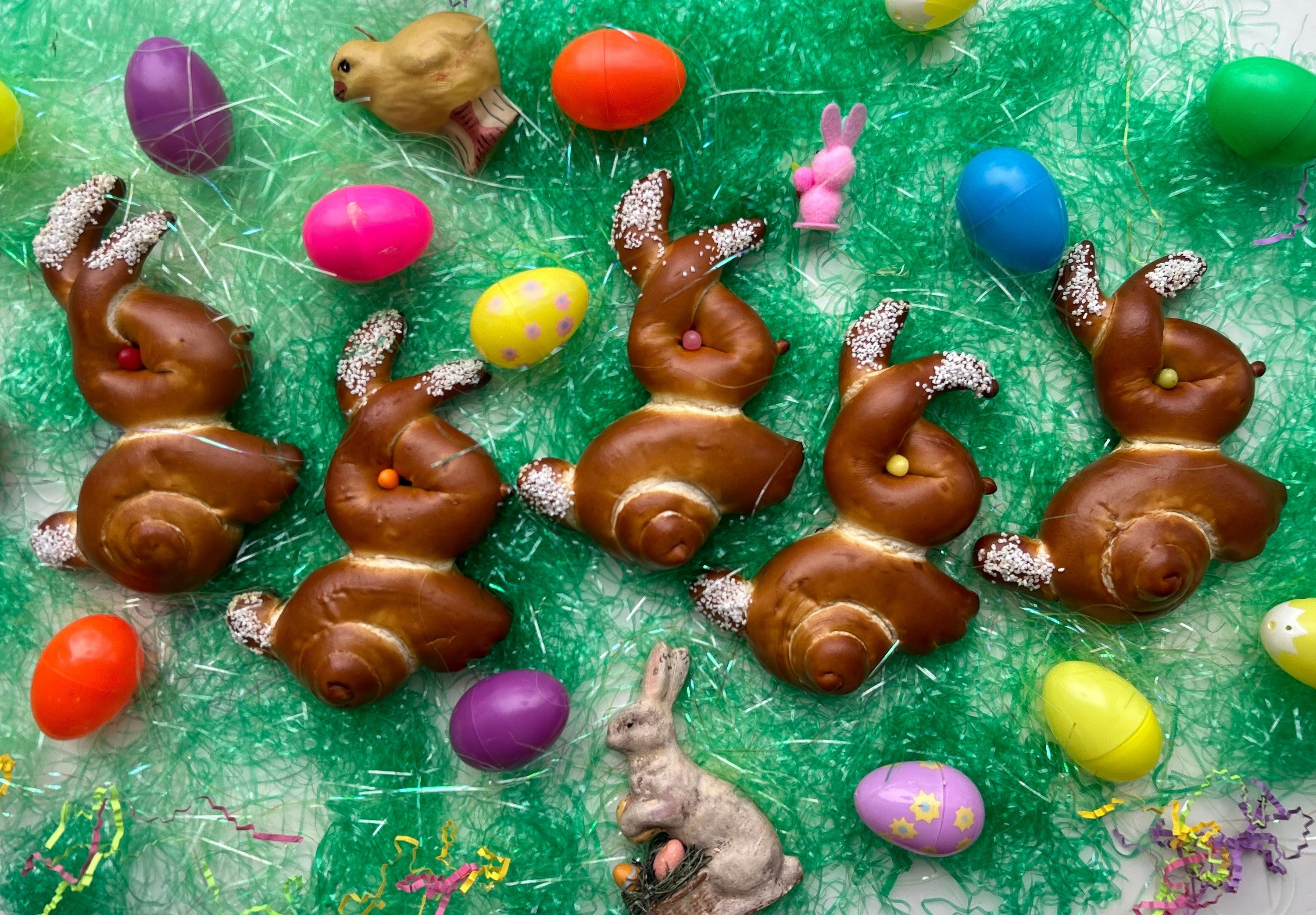 Pretzel twists in the shape of bunnies for Easter alongside Easter eggs and grass