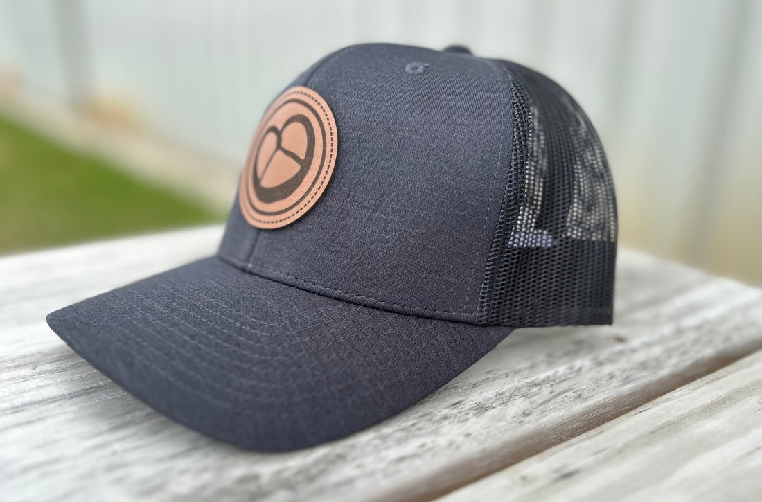 Side profile of Milwaukee Pretzel Company patch trucker hat in black with a pretzel logo